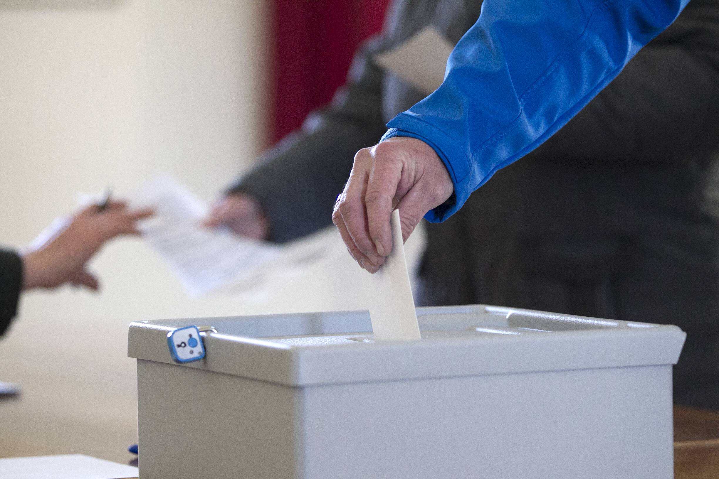 Ein Wähler steckt in einem Wahlbüro ein Wahlumschlag in eine Wahlurne (Symbolbild)