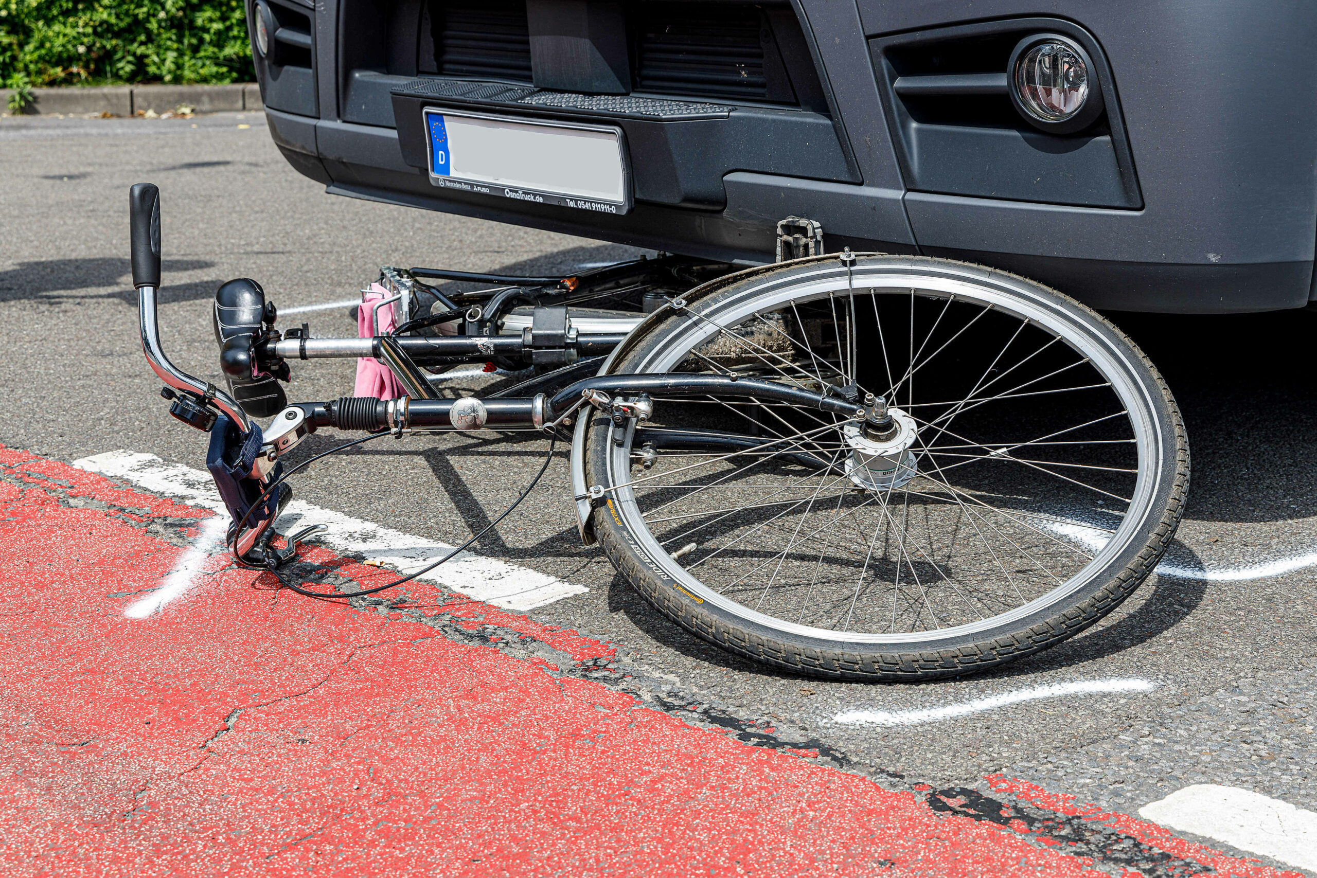 Ein Fahrrad liegt nach einem Unfall auf einer Straße unter einem Lkw.