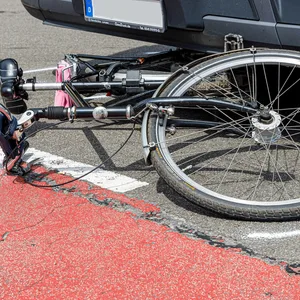 Ein Fahrrad liegt nach einem Unfall auf einer Straße unter einem Lkw.