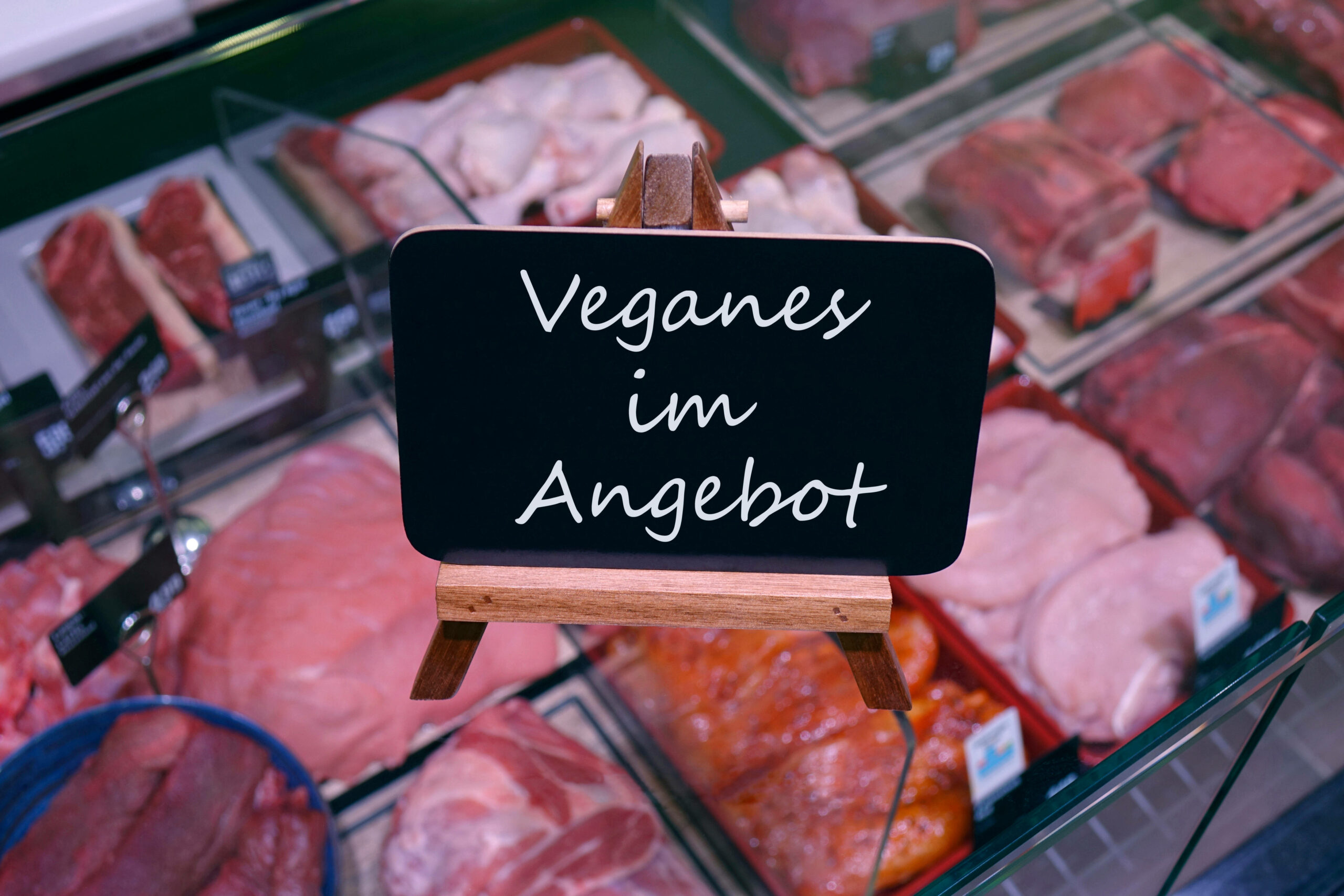 Auf einer Fleischtheke steht ein Schild mit dem Schriftzug „Veganes im Angebot“.