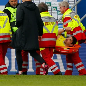 Schiedsrichter-Assistent wird auf der Liege von Sanitätern vom Feld getragenSchiedsrichter-Assistent wird auf der Liege von Sanitätern vom Feld getragen