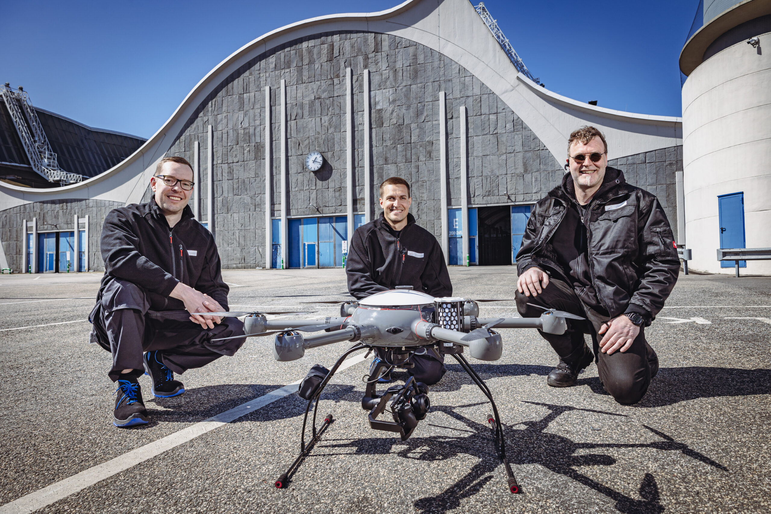 Die Drohnenpiloten Jannis von Lüde, Milan Topp und Christian Götzke (v.l.) vor der Drohne, die künftig über Straßen, Deiche und Brücken schweben soll.