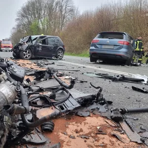 Die Trümmer eines Motorblocks liegen verstreut vor zwei Unfallwagen. Bei einer Frontalkollision zweier Autos sind sieben Menschen schwer verletzt worden.