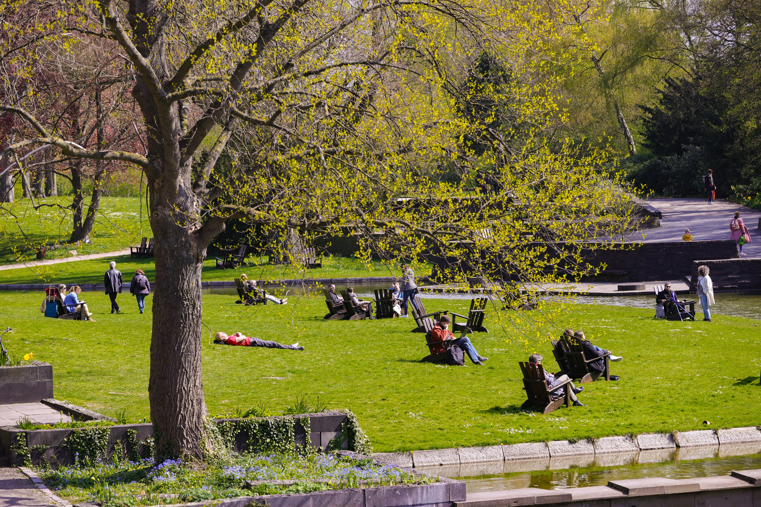 Menschen genießen im Park „Planten un Blomen“ in Hamburg die Sonne (Archivbild).