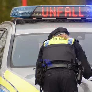 Zwei Polizisten sehen sich Papiere an, die auf der Motorhaube ihres Fahrzeugs liegen.