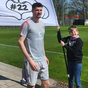 St. Pauli-Torwart Nikola Vasilj mit zwei Fans, die ein Transparent gemalt haben