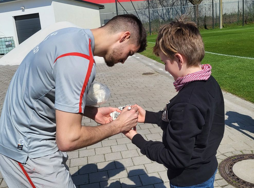 Nikola Vasilj signiert einem Fan Torwarthandschuhe