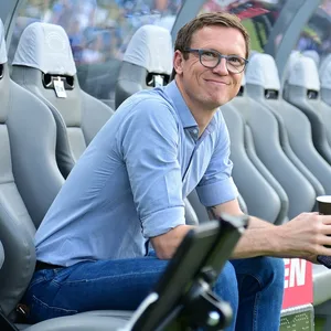Michael Mutzel grinsend auf einer Auswechselbank.