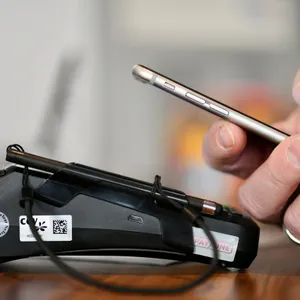 Hand hält Handy über Kartenlesegerät