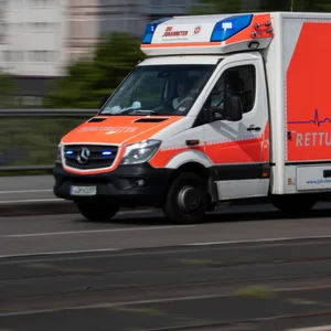 Mit eingeschaltetem Blaulicht fährt ein Rettungswagen in eine Klinik. (Symbolbild)