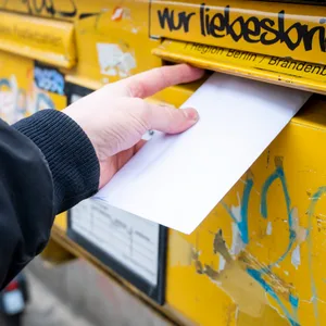 Eine Person wirft einen Brief in einen Briefkasten. Geht's nach der Post, kostet die benötigte Briefmarke bald mehr Geld. (Symbolbild)