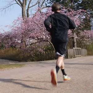 Ein Jogger in Planten und Blumen vor blühenden Japanischen Zierkirschen