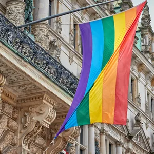 Eine Regenbogenflagge hängt über dem Eingang des Hamburger Rathauses.