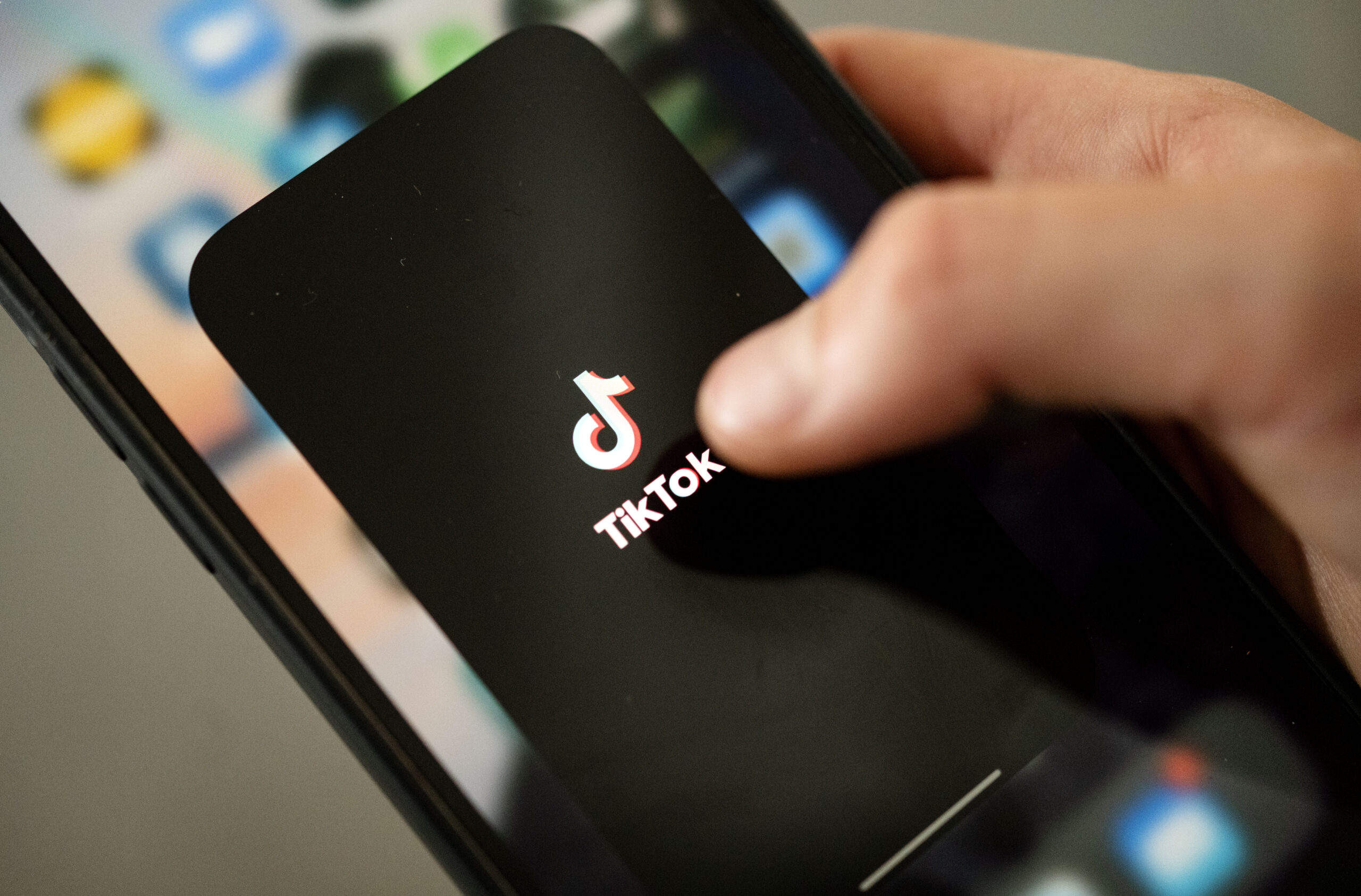 Ein Teenager tippt auf das TikTok-Logo auf einem Smartphone.