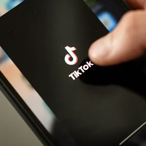 Ein Teenager tippt auf das TikTok-Logo auf einem Smartphone.