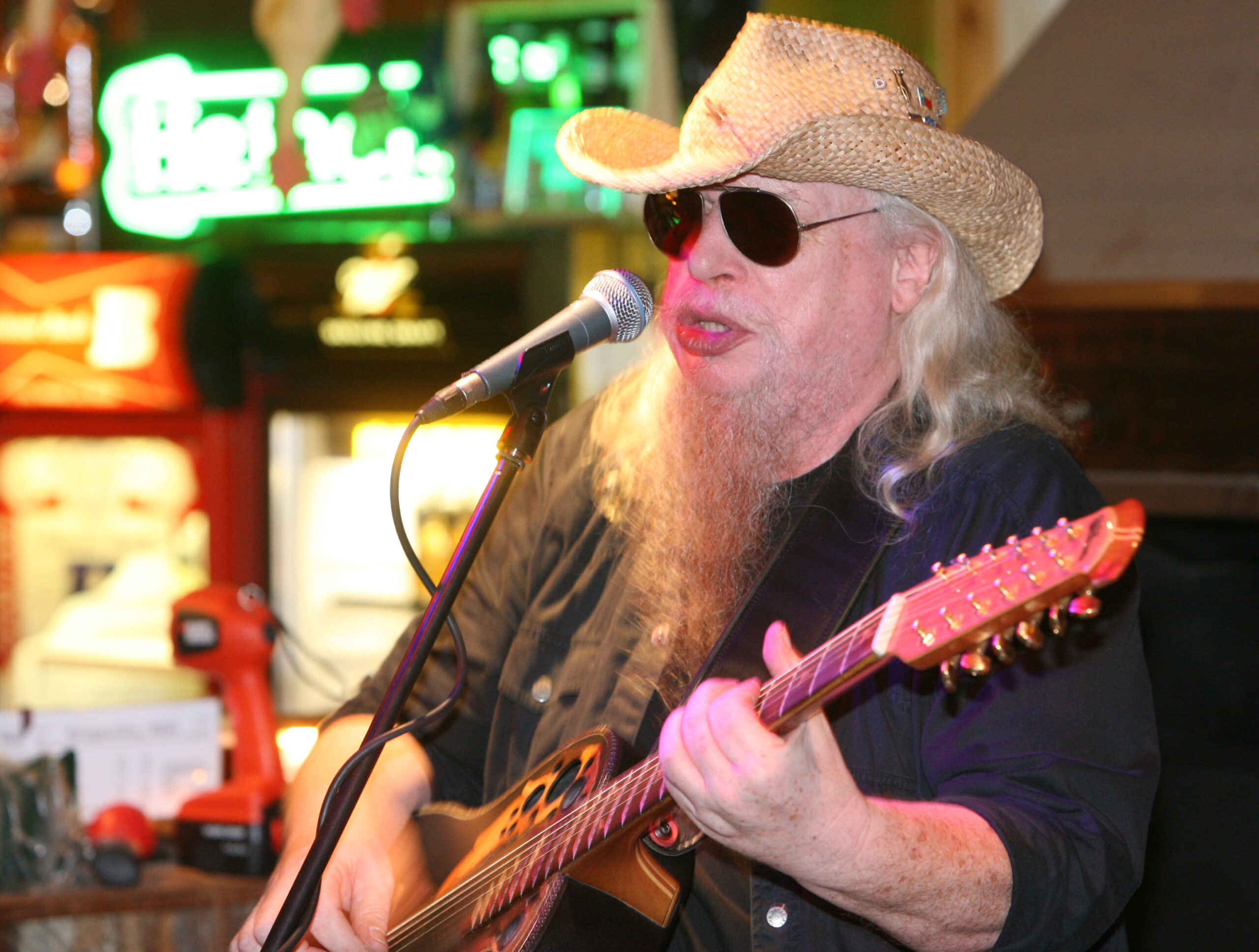 Raymond Voss sitzt Gitarre spielend in einer Bar