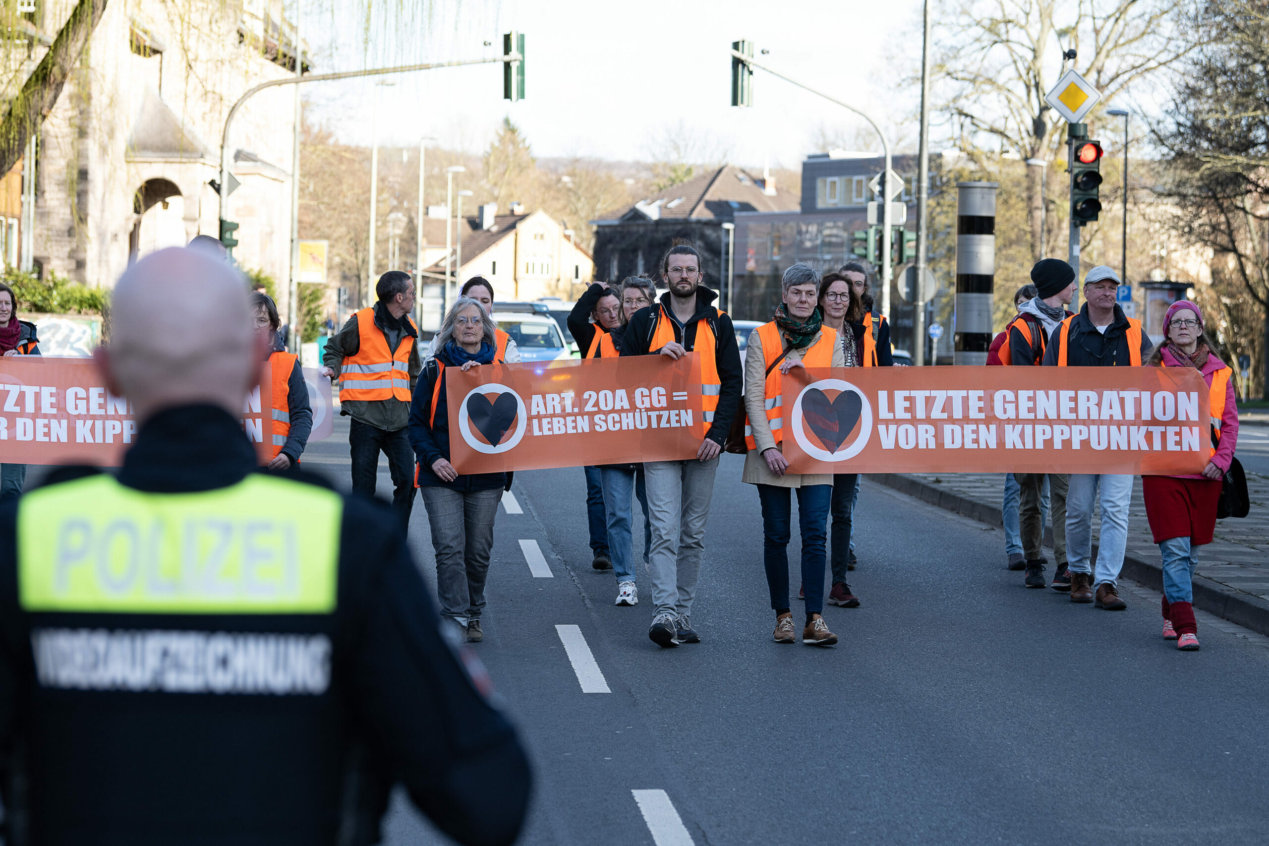 Aktivisten der Bewegung „Letzte Generation“ gehen mit Plakaten bei einem friedlichen Protestmarsch über eine Hauptverkehrsstraße