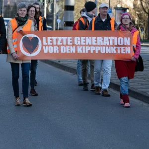 Aktivisten der Bewegung „Letzte Generation“ gehen mit Plakaten bei einem friedlichen Protestmarsch über eine Hauptverkehrsstraße