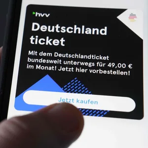 Ein Mann tippt auf seinem Smartphone auf die HVV-Switch-App, um das Deutschlandticket zu kaufen.