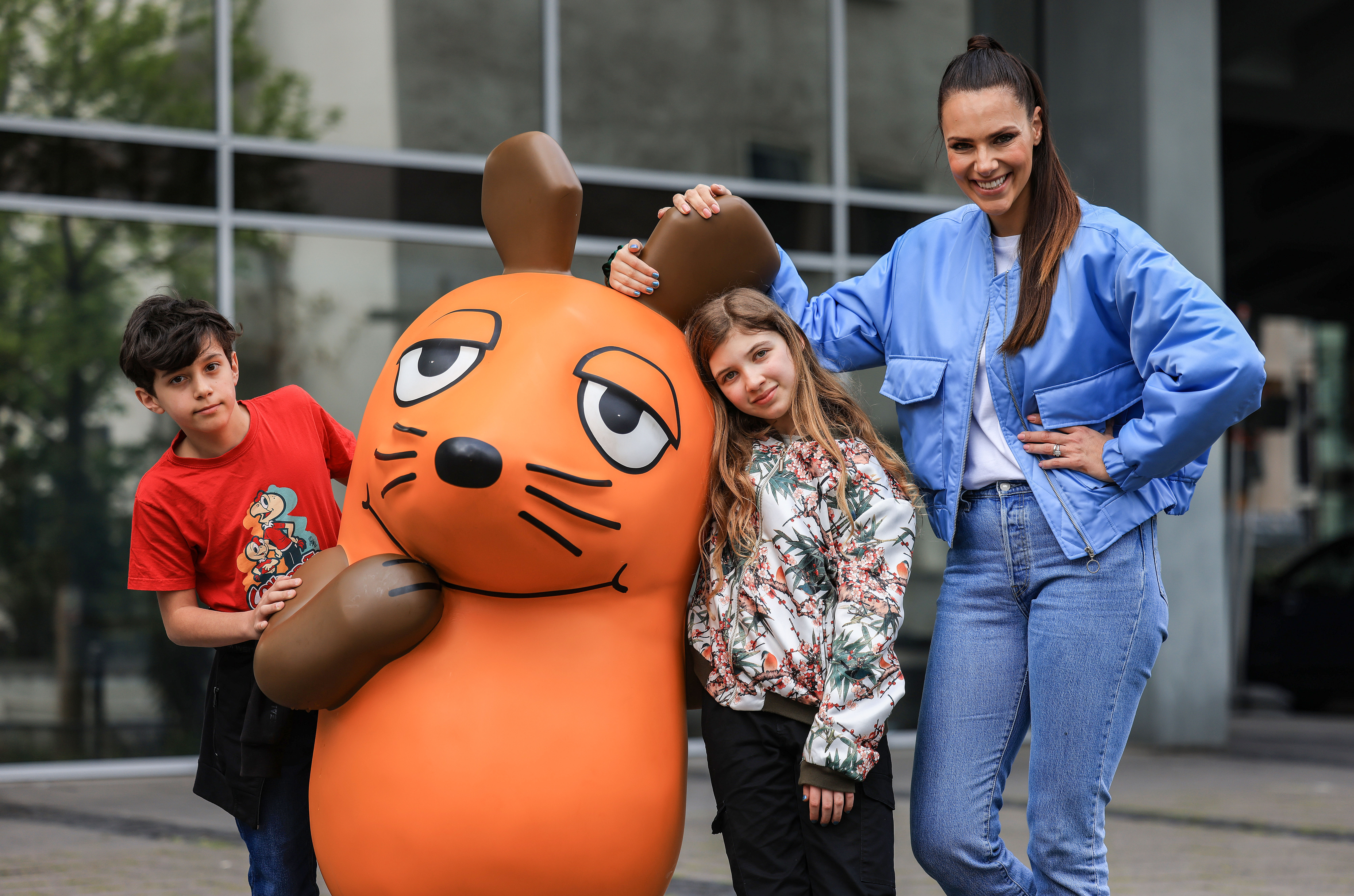 Die Fernsehmoderatorin Esther Sedlaczek (r) steht mit Kindern an der Maus-Figur.