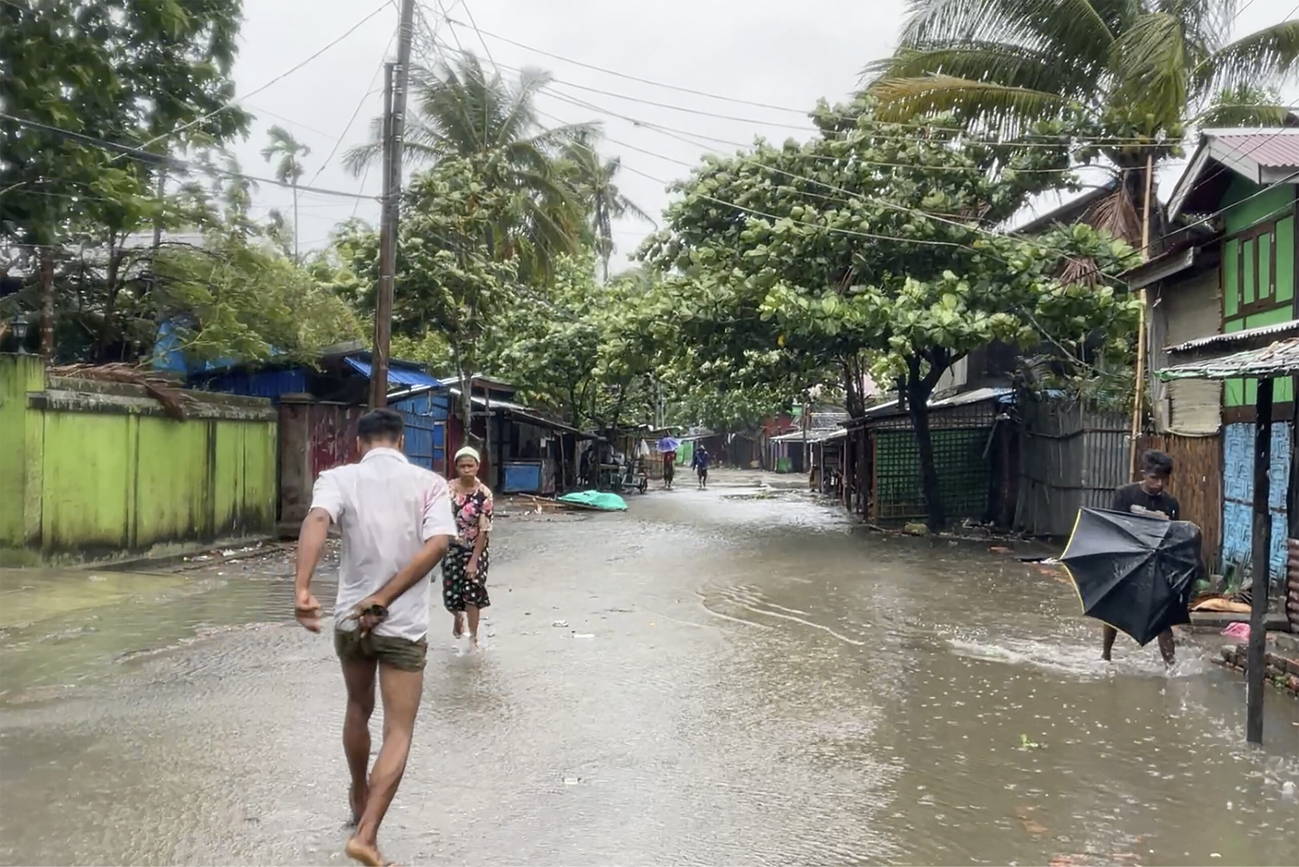Menschen gehen auf einer durch starken Regen überfluteten Straße, während sich der Zyklon Mocha der Region nähert.