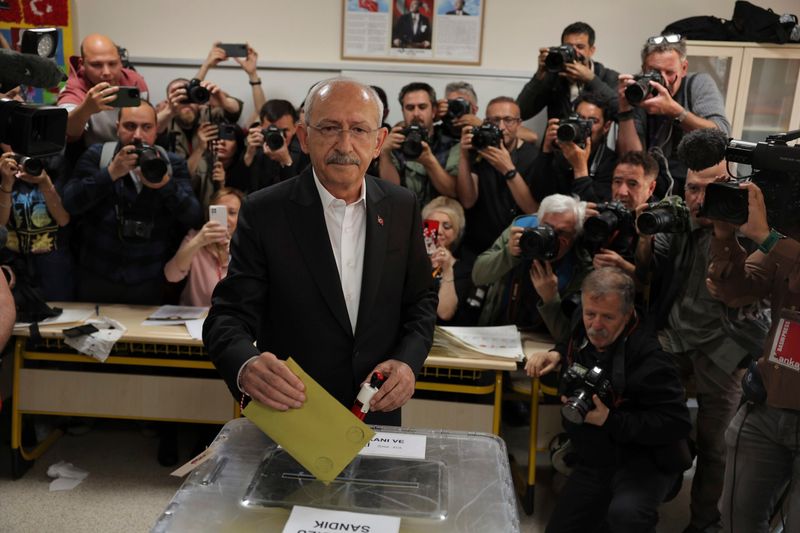 Kemal Kilicdaroglu gibt seinen Stimmzettel in einem Wahllokal in eine Wahlurne, Kameras im Hintergrund.