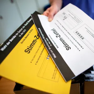 Ein Wahlhelfer gibt in einem Wahllokal die Stimmzettel für die Bürgerschaftswahl und die Kommunalwahl an die Wähler aus.