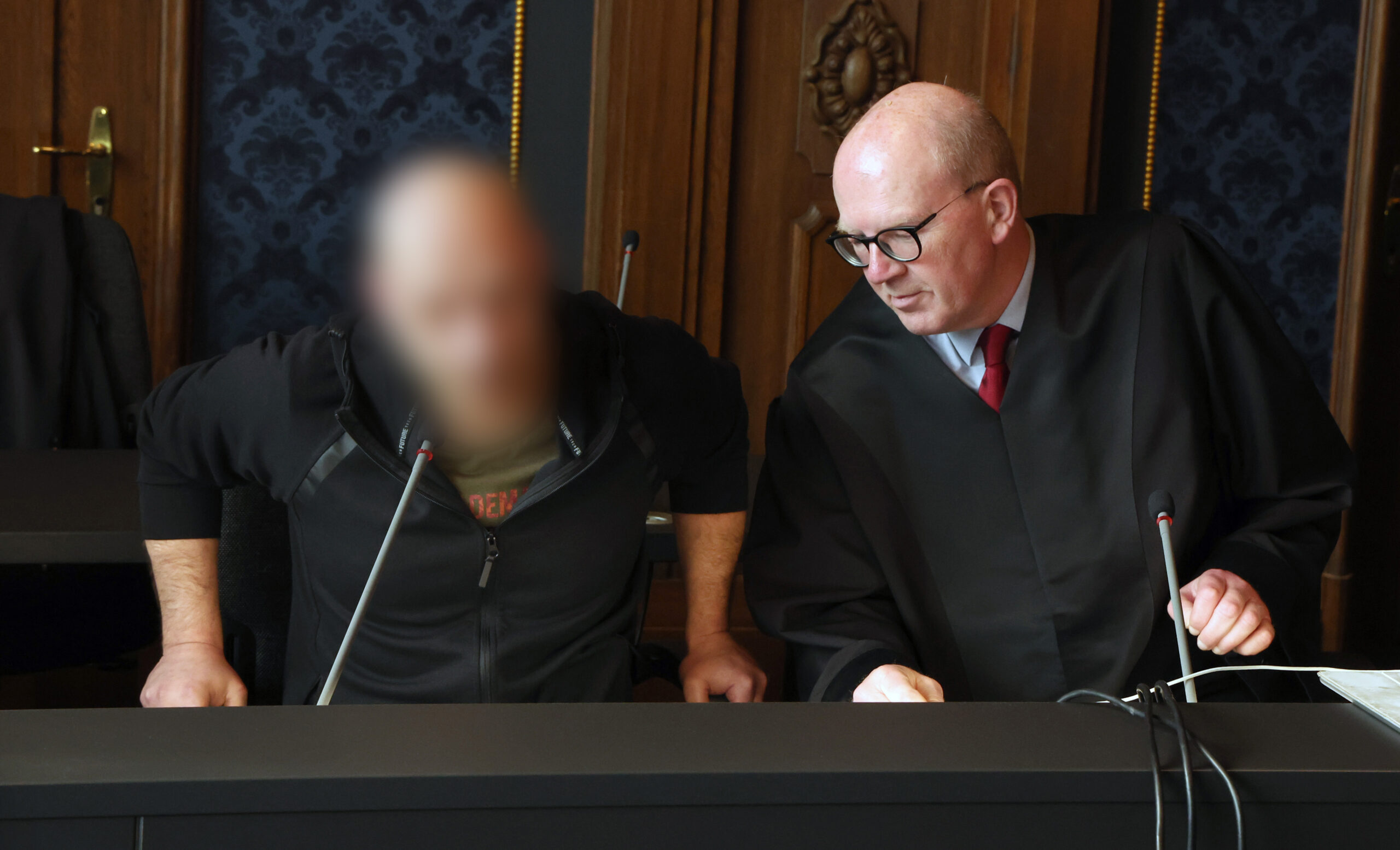 Der Angeklagte (l-r) im Totschlagprozess und Andreas Roter, Rechtsanwalt, nehmen vor dem Prozessauftakt im Saal des Landgerichts Schwerin Platz.