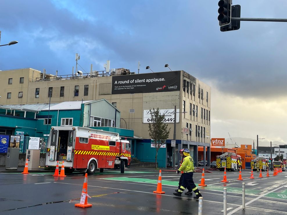 Einsatzkräfte der Feuerwehr gehen nach dem Brand vor dem Hostel entlang.