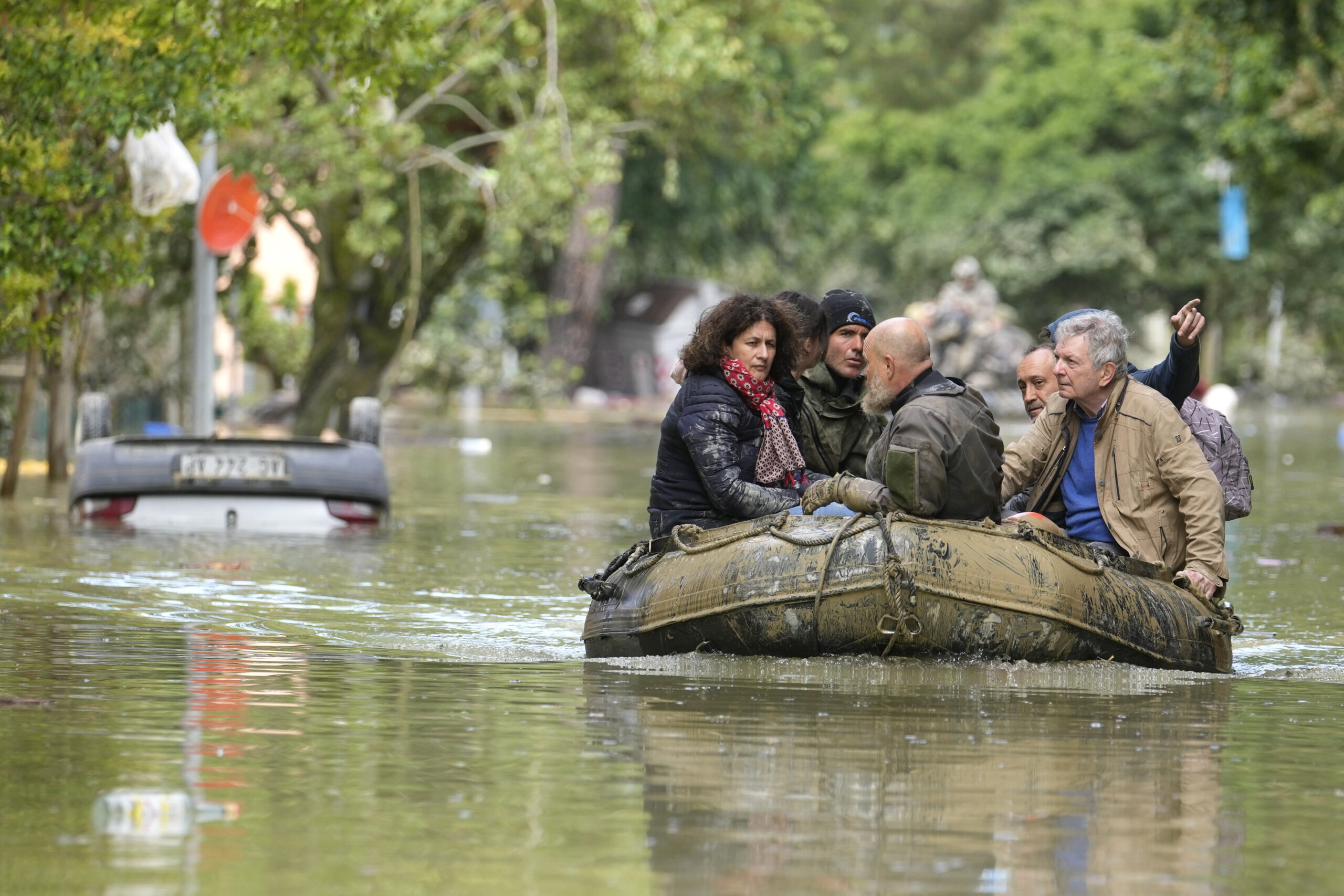 Menschen auf einem Schlauchboot fahren über ein überschwemmtes Gebiet