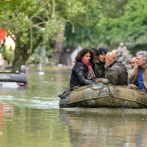Menschen auf einem Schlauchboot fahren über ein überschwemmtes Gebiet