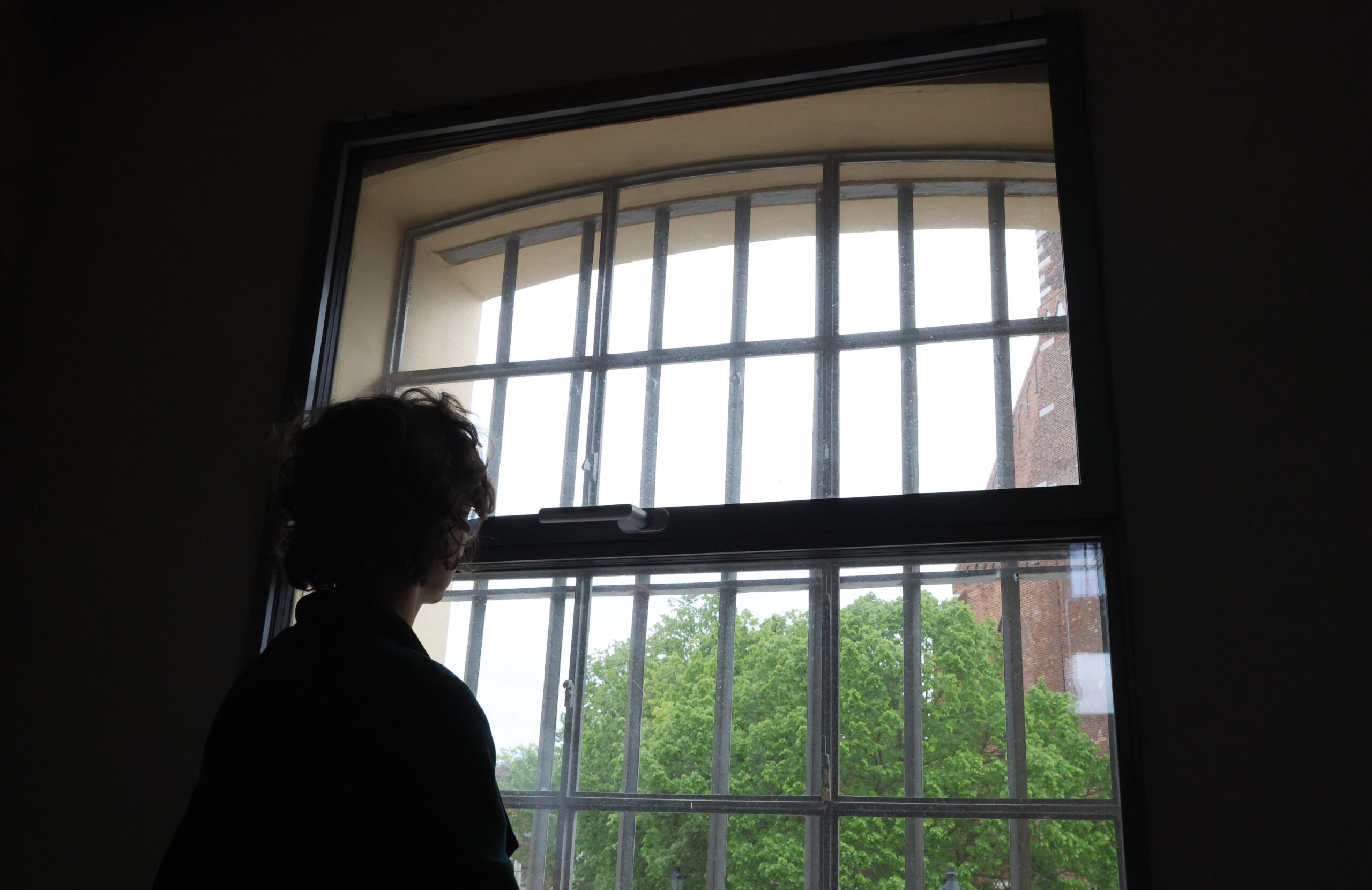 Person steht vor Fenster mit Gittern