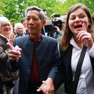 Sucharit Bhakdi und seine Ehefrau Katharina Reiss gehen durch eine Gruppe von wartenden Menschen und Journalisten.