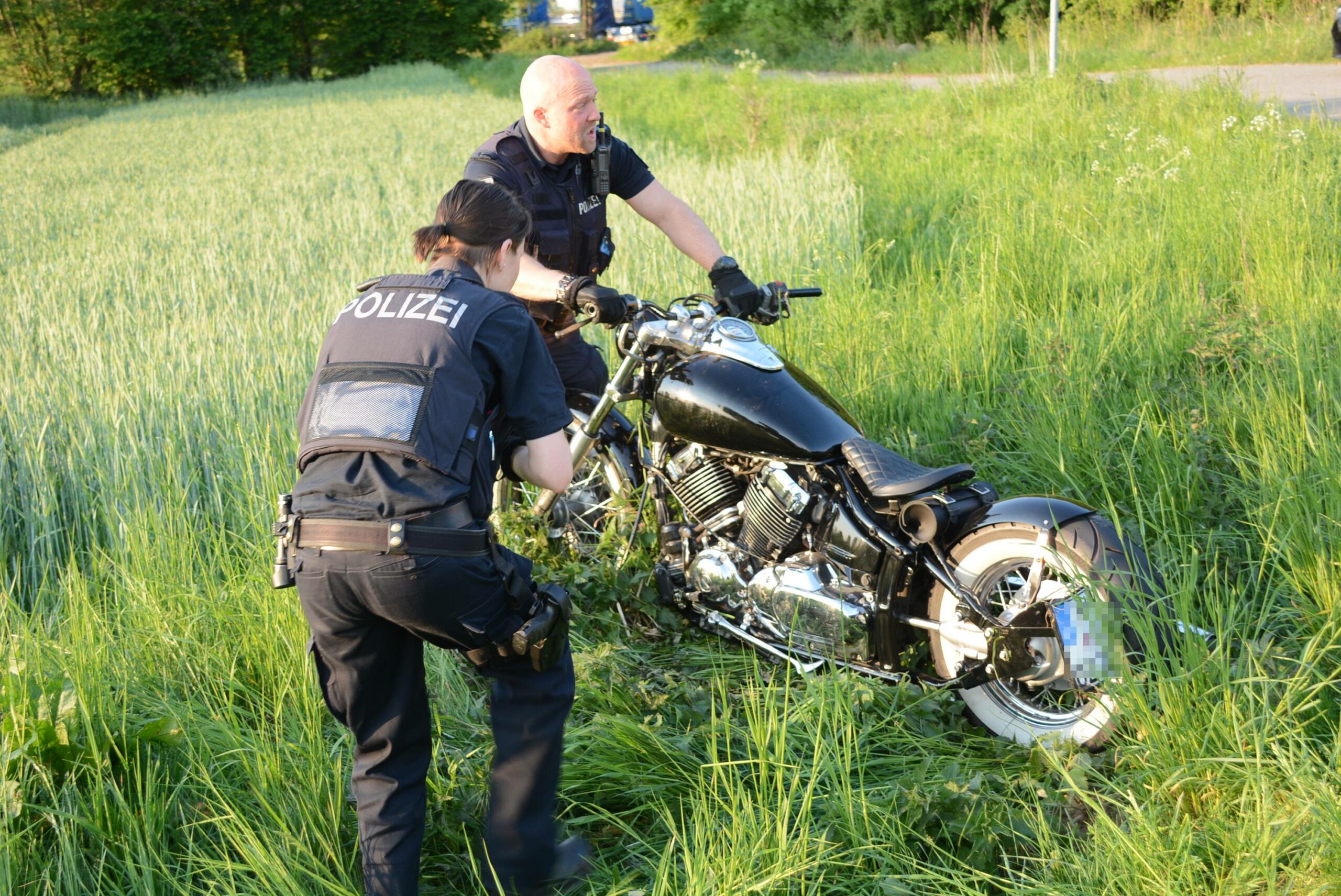 Polizeibeamte richten die Harley-Davidson wieder auf.