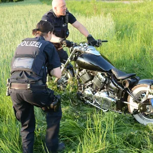 Polizeibeamte richten die Harley-Davidson wieder auf.