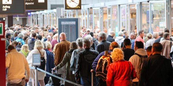 Reisende warten in langen Schlangen vor der Sicherheitskontrolle am Flughafen Hamburg auf die Abfertigung.