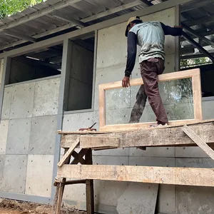 Ein Mann arbeitet am Rohbau eines einfachen Hauses, bei dem gebrauchte Windeln einen Teil des Baumaterials ersetzen