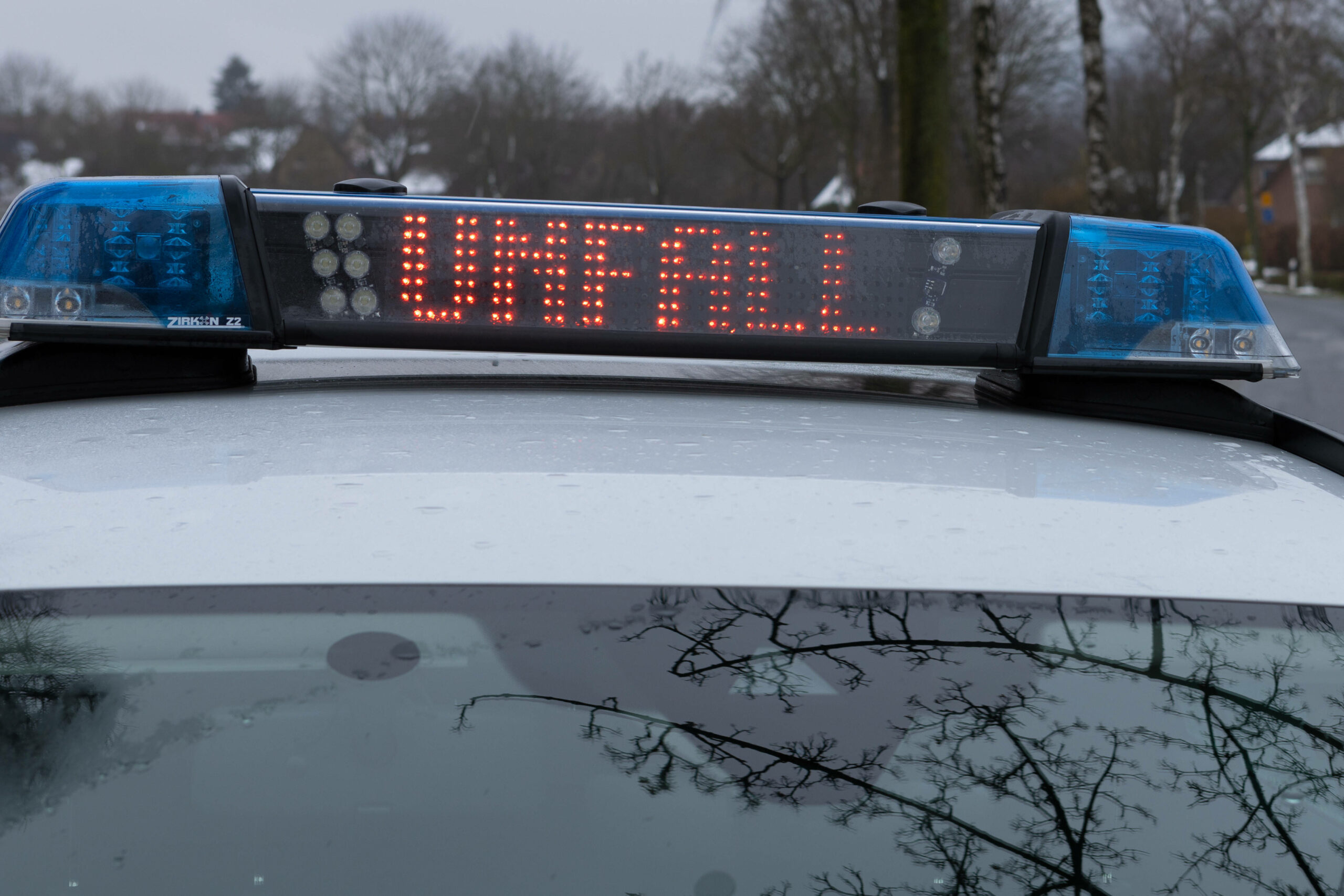 Ein Einsatzfahrzeug, Streifenwagen, der Polizei steht mit Blaulicht und dem Schriftzug Unfall in Display an einer Unfallstelle