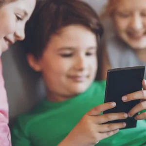 Kinder blicken auf ein Smartphone: Der Verein „Smarter Start ab 14“ setzt sich dafür ein, dass Kinder erst mit 14 Jahren ein eigenes Handy bekommen.