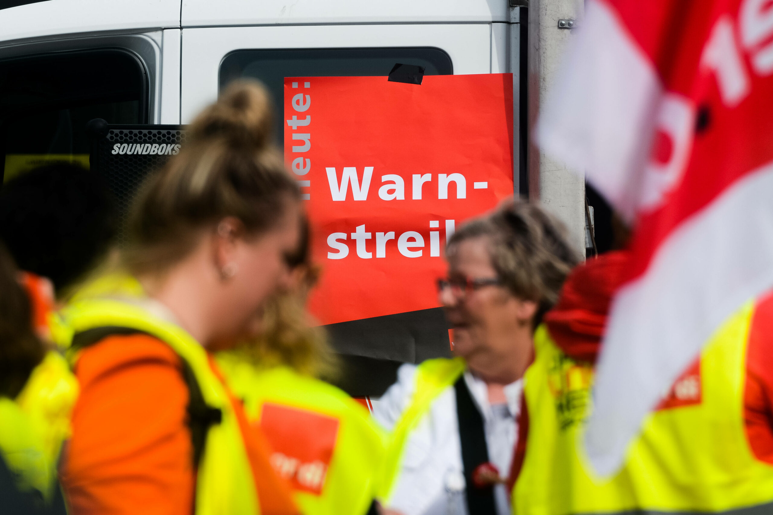Streikende stehen vor einem Schild mit der Aufschrift: Heute - Warnstreik
