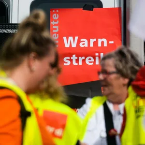 Streikende stehen vor einem Schild mit der Aufschrift: Heute - Warnstreik