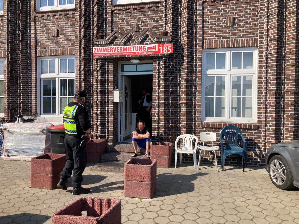 Einer der vielen Arbeiter, die hier nur vorübergehend wohnen sollen, sitzt auf den Stufen vor dem Eingang des Gebäudes.