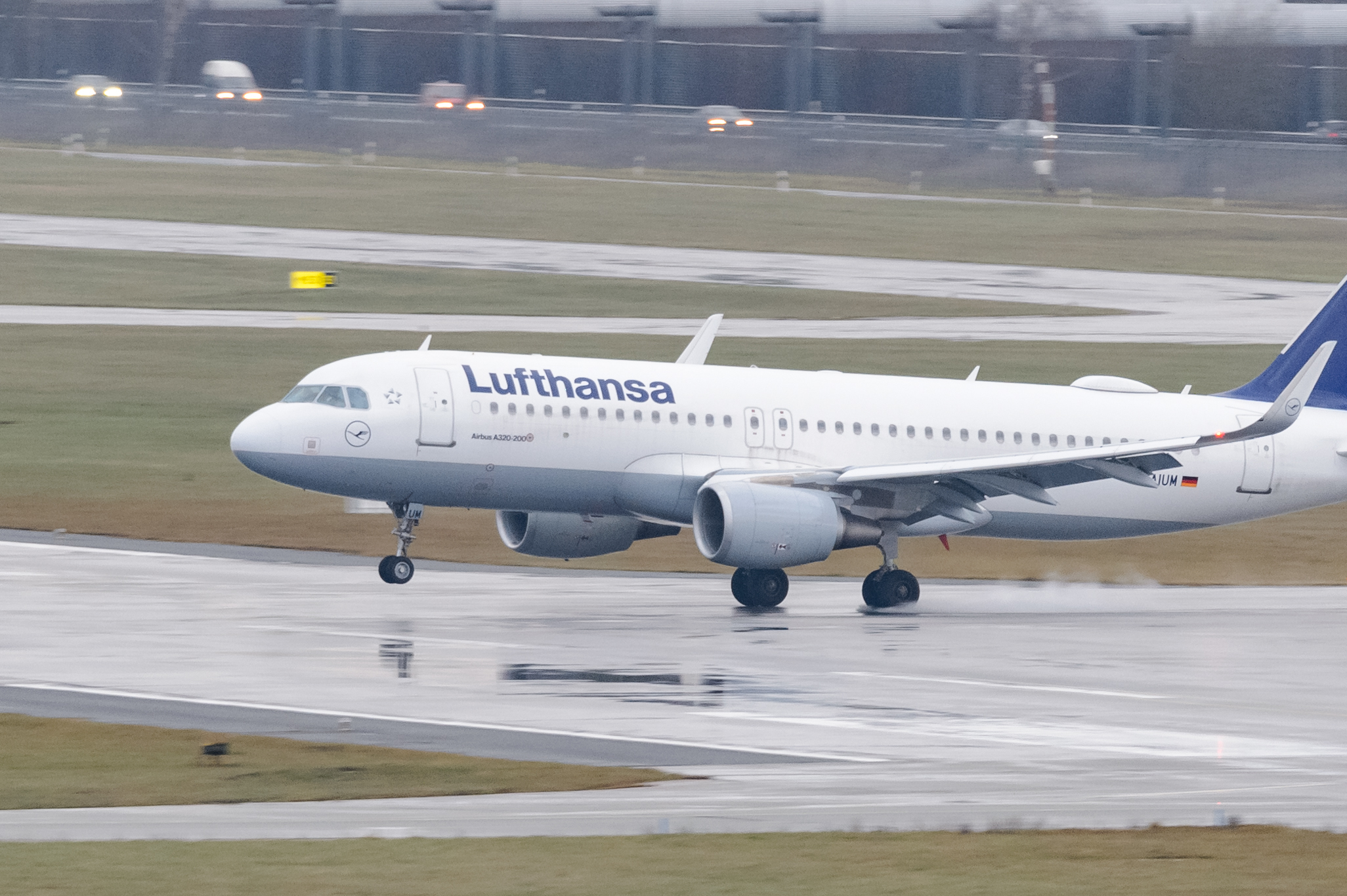 Ein Airbus A320 der Fluggesellschaft Lufthansa landet auf dem nassen Rollfeld.
