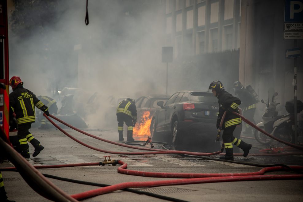 Feuerwehrleute löschen Autos nach einer Explosion in der Mailänder Innenstadt.