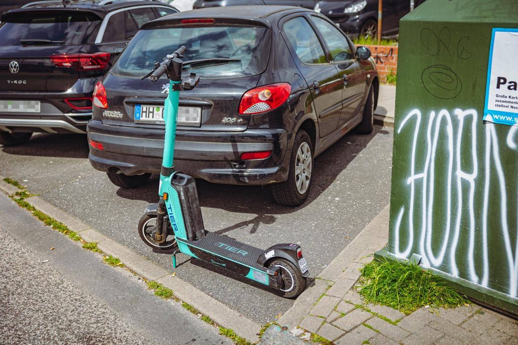 Keine Rücksicht: Ein E-Scooter ist hinter einem geparkten Auto abgestellt worden.