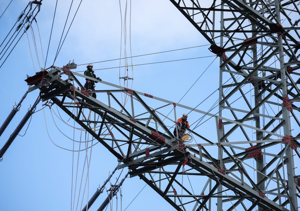 Monteure befestigen Seile auf einem Strommast