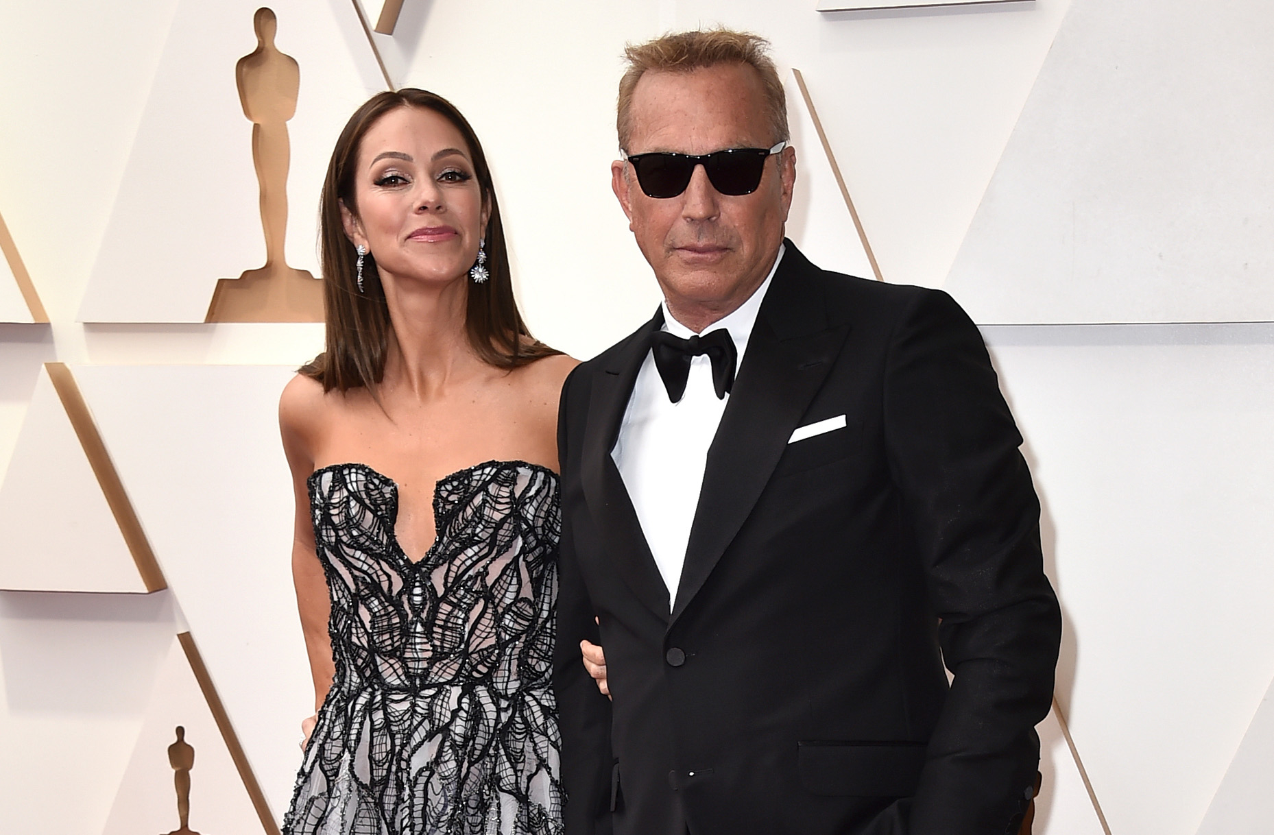 Kevin Costner im Anzug und Christine Baumgartner im Abendkleid stehen auf einem red carpet