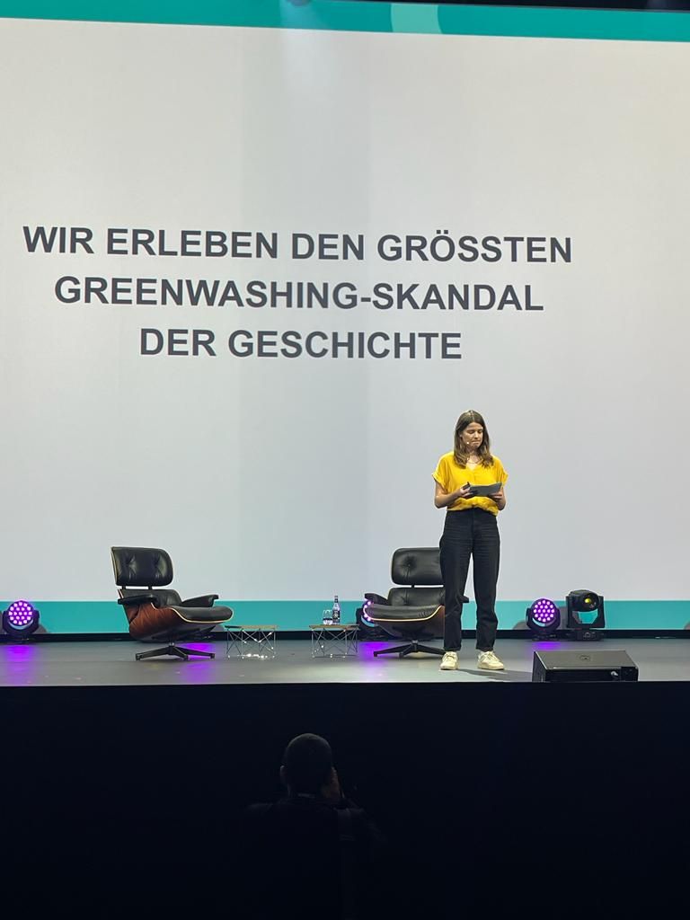 Luisa Neubauer auf der OMR-Bühne, hinter ihr steht: „Wir erleben den größten Greenwashing-Skandal der Geschichte“