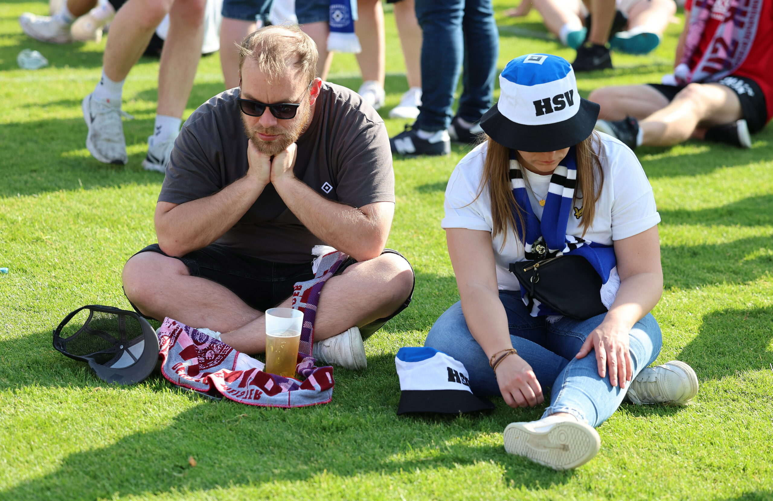 Zwei HSV-Fans sitzen enttäuscht auf dem Rasen in Sandhausen.
