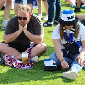 Zwei HSV-Fans sitzen enttäuscht auf dem Rasen in Sandhausen.